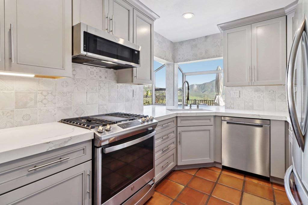 9863 Avenida Colino Spring Valley, CA 91977 - Photo 10 of 54 a kitchen with stainless steel appliances granite countertop a stove a sink and a microwave