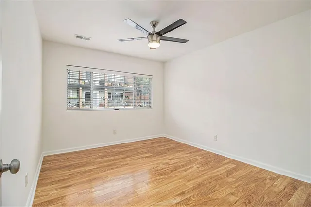 an empty room with wooden floor and ceiling fan