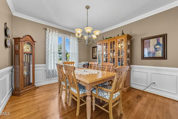 a dining room with wooden floor a chandelier a wooden table and chairs