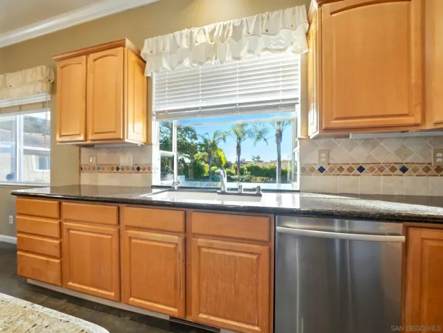 a kitchen with granite countertop white cabinets and a window