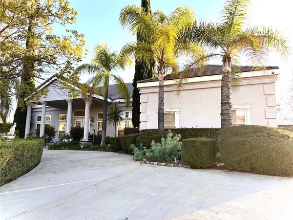 a front view of a house with a yard and palm trees