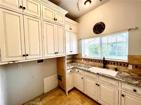 a large white kitchen with granite countertop a sink and cabinets