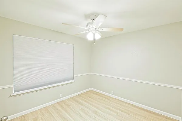 an empty room with a window and a fan