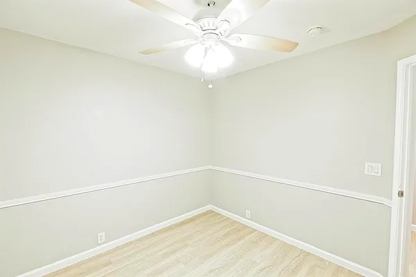 a view of a room with wooden floor and a chandelier fan