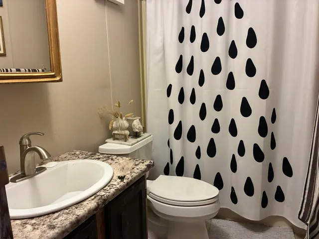 a bathroom with a granite countertop toilet a sink and a mirror