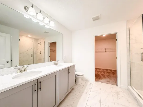 a spacious bathroom with a double vanity sink a toilet and a mirror