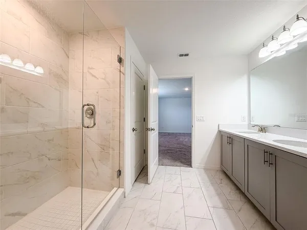 a bathroom with a double vanity sink mirror and shower