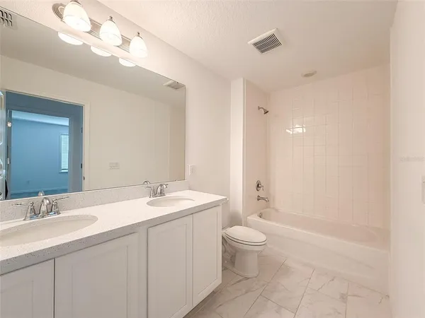 a bathroom with a double vanity sink a toilet and a mirror