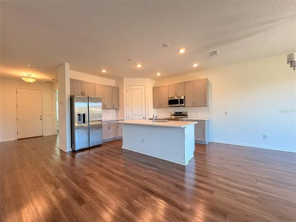 a large kitchen with a center island wooden floor stainless steel appliances and a window