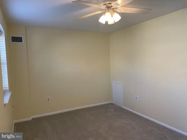 an empty room with a chandelier fan and windows