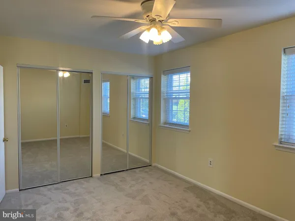a view of an empty room with window and chandelier fan