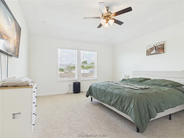 a spacious bedroom with a bed a window and a chandelier