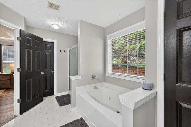 a spacious bathroom with a tub sink and mirror