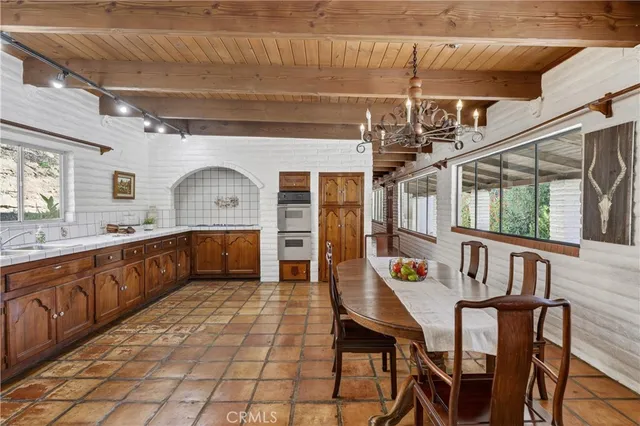 a kitchen with stainless steel appliances kitchen island granite countertop a dining table chairs in it and wooden floors