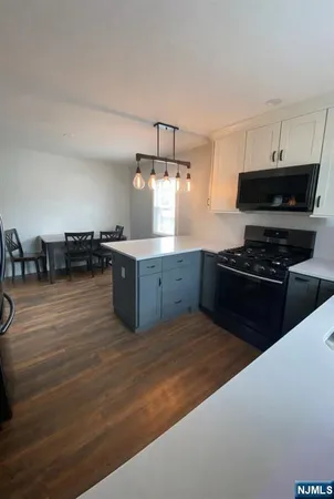 a kitchen with stainless steel appliances a stove a sink a refrigerator and chairs