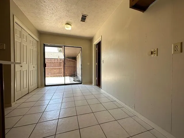 a view of an empty room with window and chandelier fan