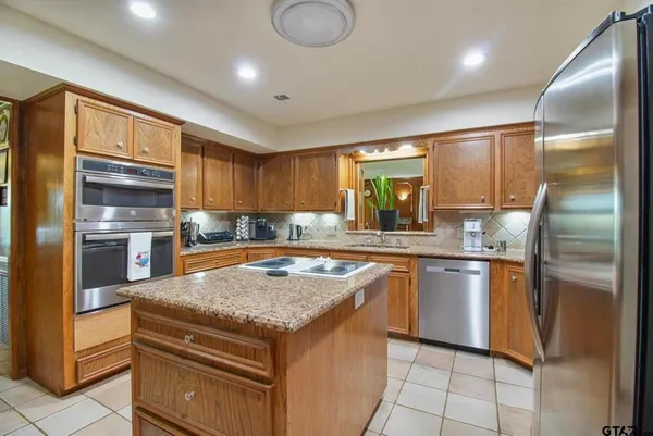 a kitchen with stainless steel appliances granite countertop a sink and a refrigerator