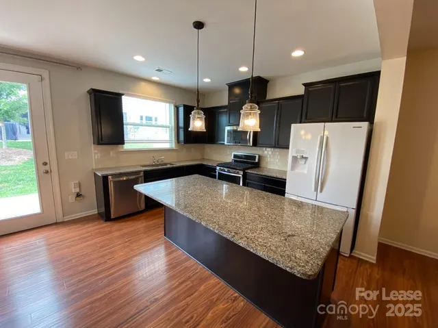 a large kitchen with stainless steel appliances a large counter top and wooden floor