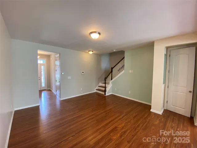 an empty room with wooden floor and staircase