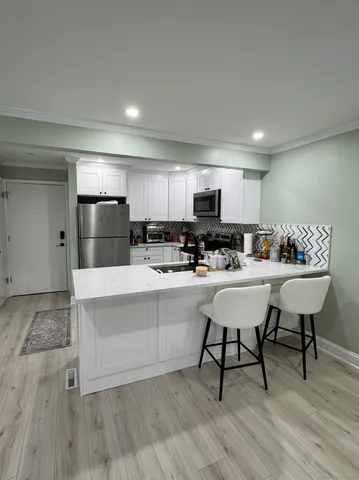 a living room with stainless steel appliances furniture a refrigerator and kitchen view