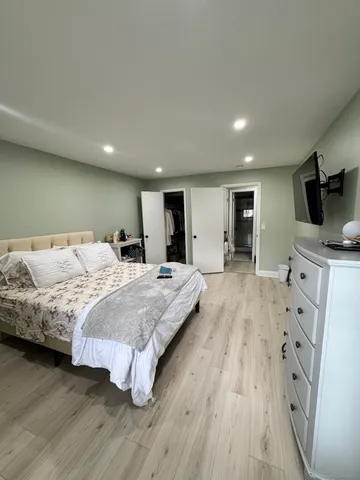 a spacious bedroom with a large bed and a flat tv screen on a dresser