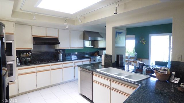 a kitchen with kitchen island granite countertop a sink stainless steel appliances and cabinets