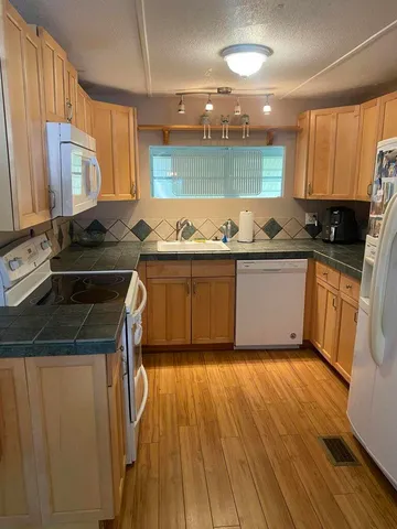 a kitchen with stainless steel appliances granite countertop a sink and wooden cabinets