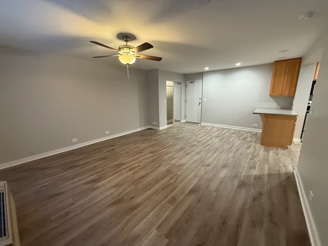 a view of a livingroom with a chandelier fan and wooden floor