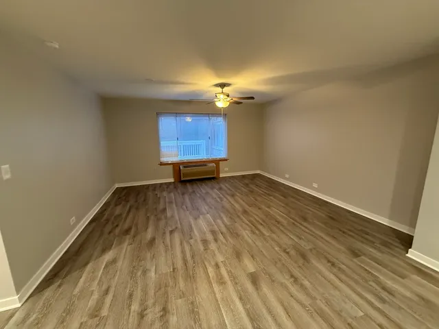 a view of empty room with wooden floor and fan
