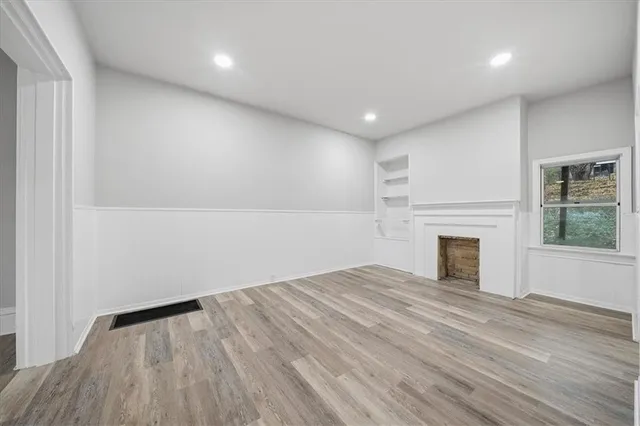 a view of empty room with wooden floor and fireplace