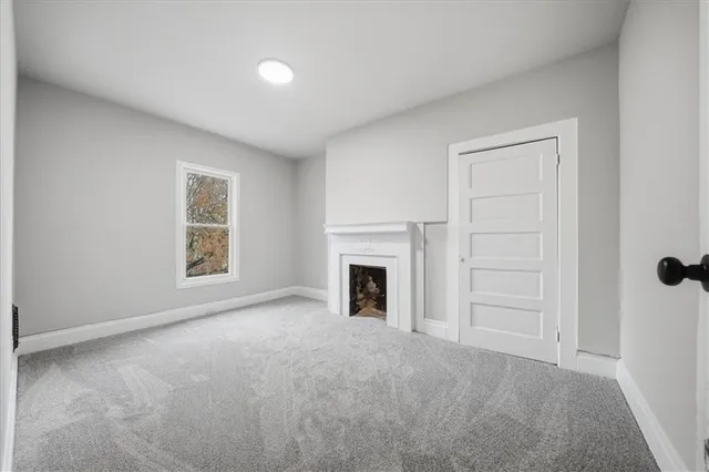 an empty room with windows and fireplace