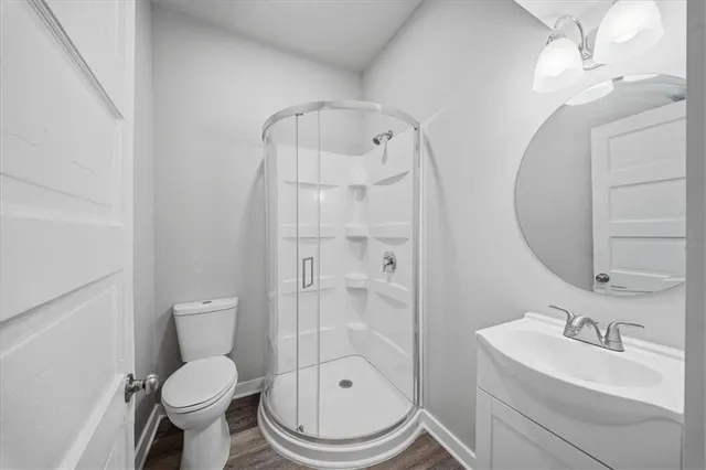a bathroom with a toilet a sink a mirror and a shower