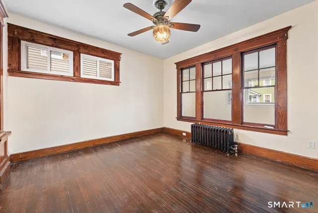a view of an empty room with a window and wooden floor