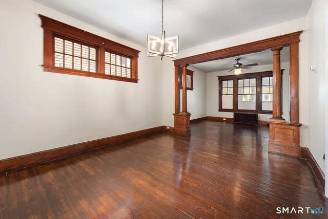 a view of an empty room with window and wooden floor