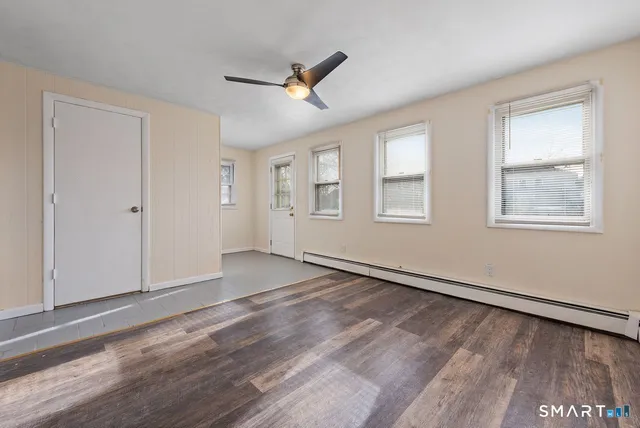a view of an empty room with wooden floor and a window