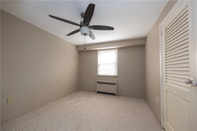 an empty room with chandelier fan and windows