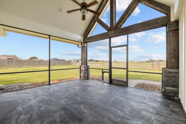 a view of an empty room with wooden floor and windows