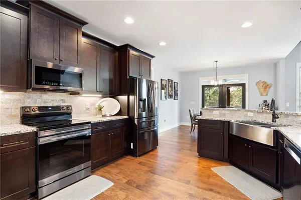 a large kitchen with stainless steel appliances granite countertop a stove refrigerator sink and cabinets