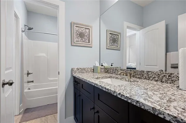 a bathroom with a granite countertop sink and a bathtub