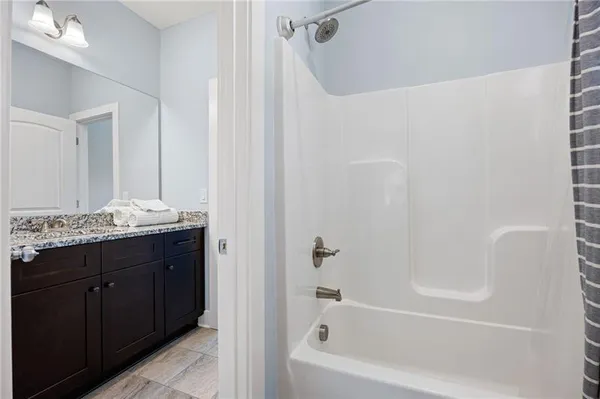 a bathroom with a granite countertop sink a mirror and a bathtub