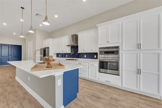 a kitchen with stainless steel appliances kitchen island granite countertop a sink dishwasher a stove and a refrigerator with wooden floor