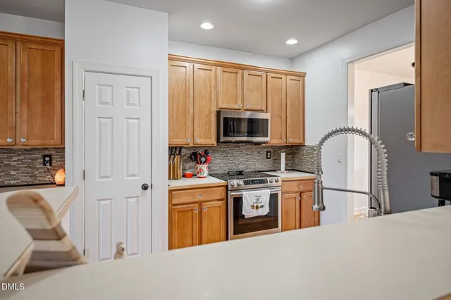 a kitchen with stainless steel appliances granite countertop a stove a sink dishwasher a refrigerator and a microwave oven with white cabinets