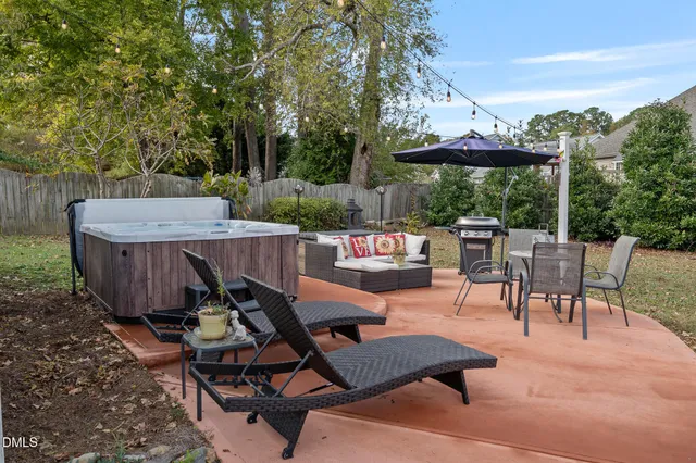 a view of a patio with table and chairs under an umbrella with large trees
