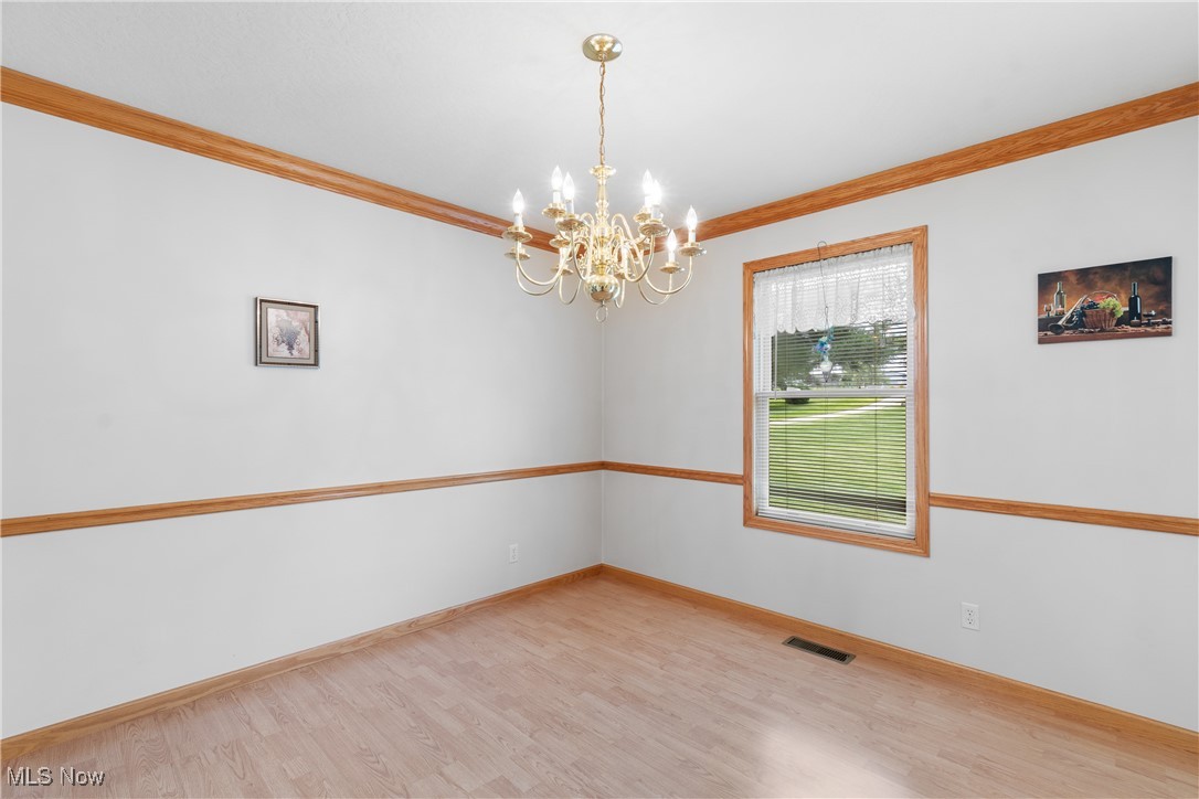 889 Martin Road Mogadore, OH 44260 - Photo 13 of 33 Spare room with a chandelier, ornamental molding, and wood finished floors