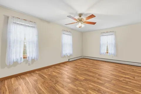 a view of an empty room with window and a chandelier fan