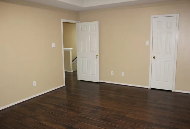 a view of an empty room with wooden floor and closet