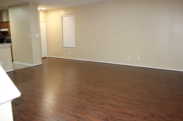 a view of an empty room with wooden floor and a window