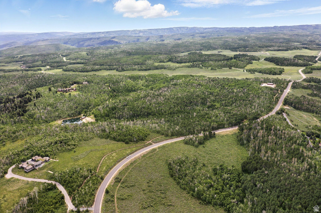 1555 North Wolf Creek Ranch Road, Unit 11 Heber City, UT 84036 - Photo 7 of 9 Expansive aerial landscape featuring a winding paved road, lush green tree coverage, distant mountainous terrain, a visible body of water, and residential structures