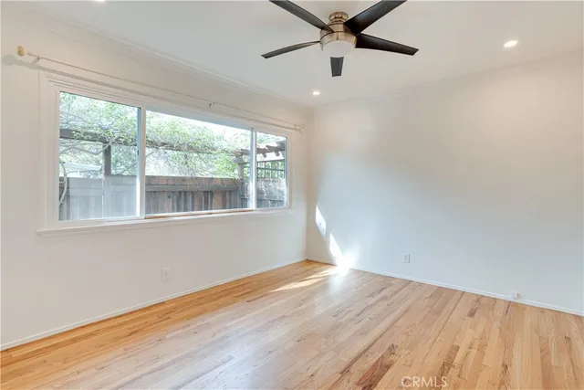 an empty room with wooden floor fan and windows
