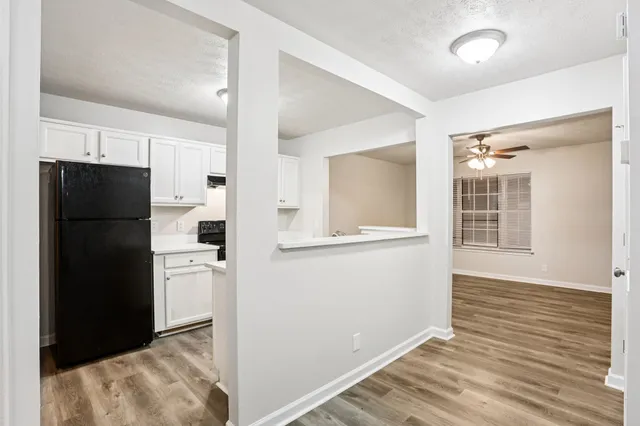 a view of a kitchen with refrigerator and wooden floor